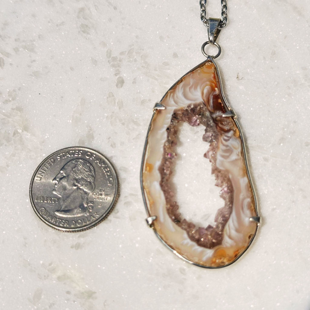 Agate Geode crystal necklace next to a quarter for size reference