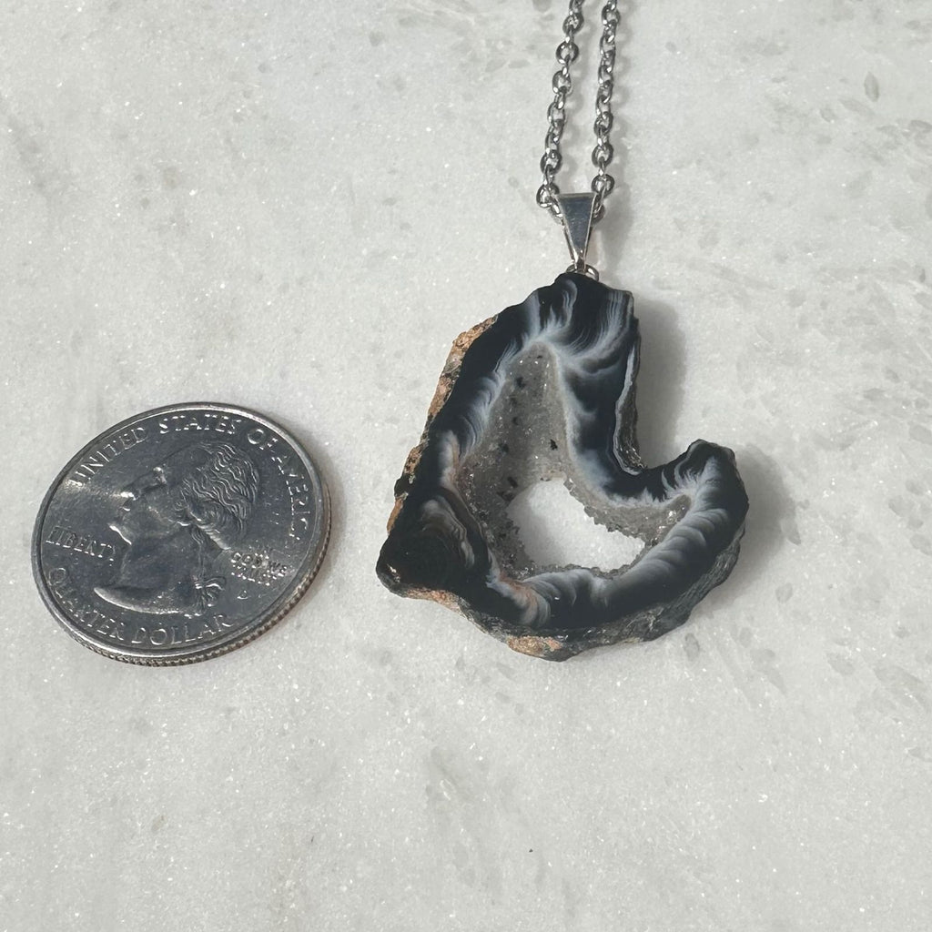 raw Agate geode slice next to a quarter for size reference 