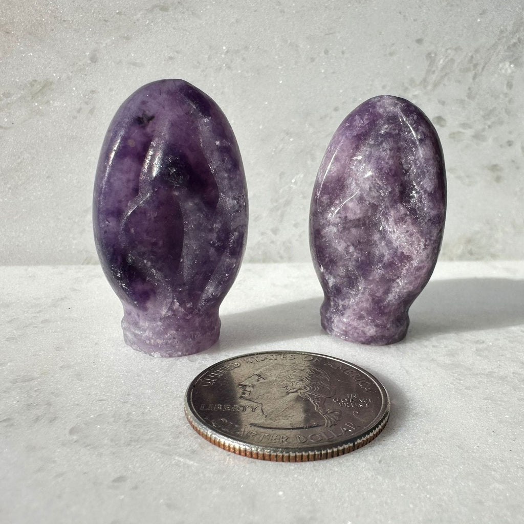 Lepidolite crystal vulva carving, aka Portal to Paradise, next to a quarter for size reference