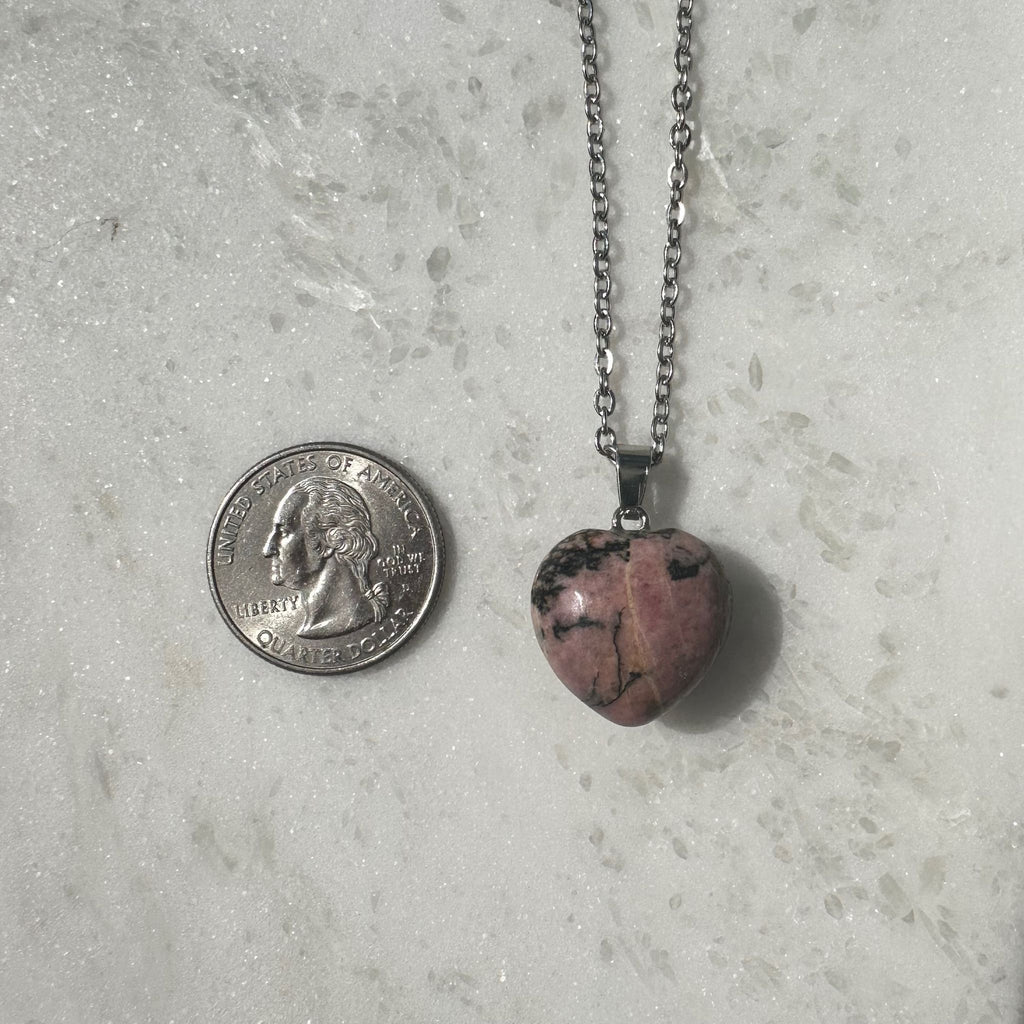 Rhodonite Crystal Heart Necklace next to a quarter for size reference