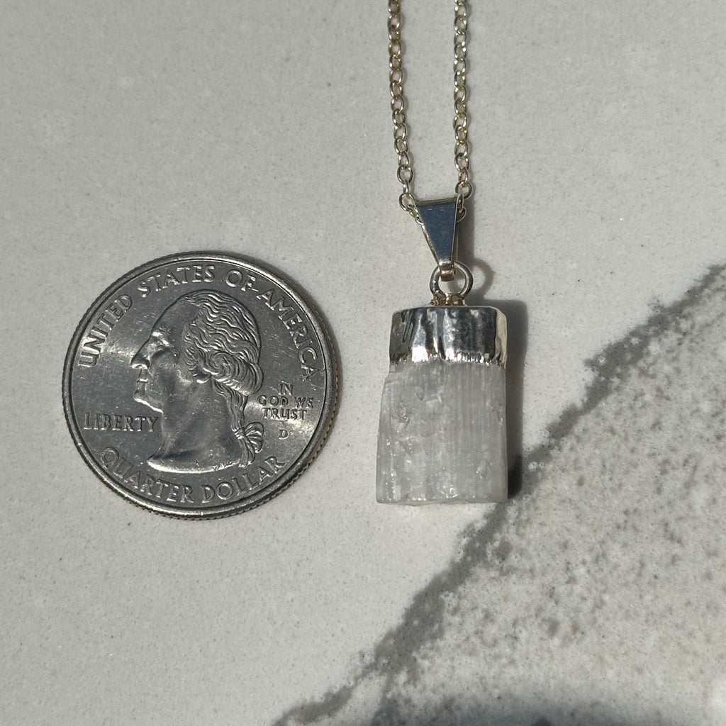 Selenite pendant next to quarter for size reference