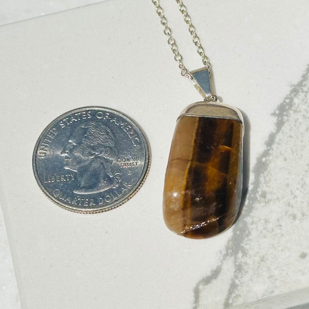 Tigers Eye pendant next to a quarter for size reference