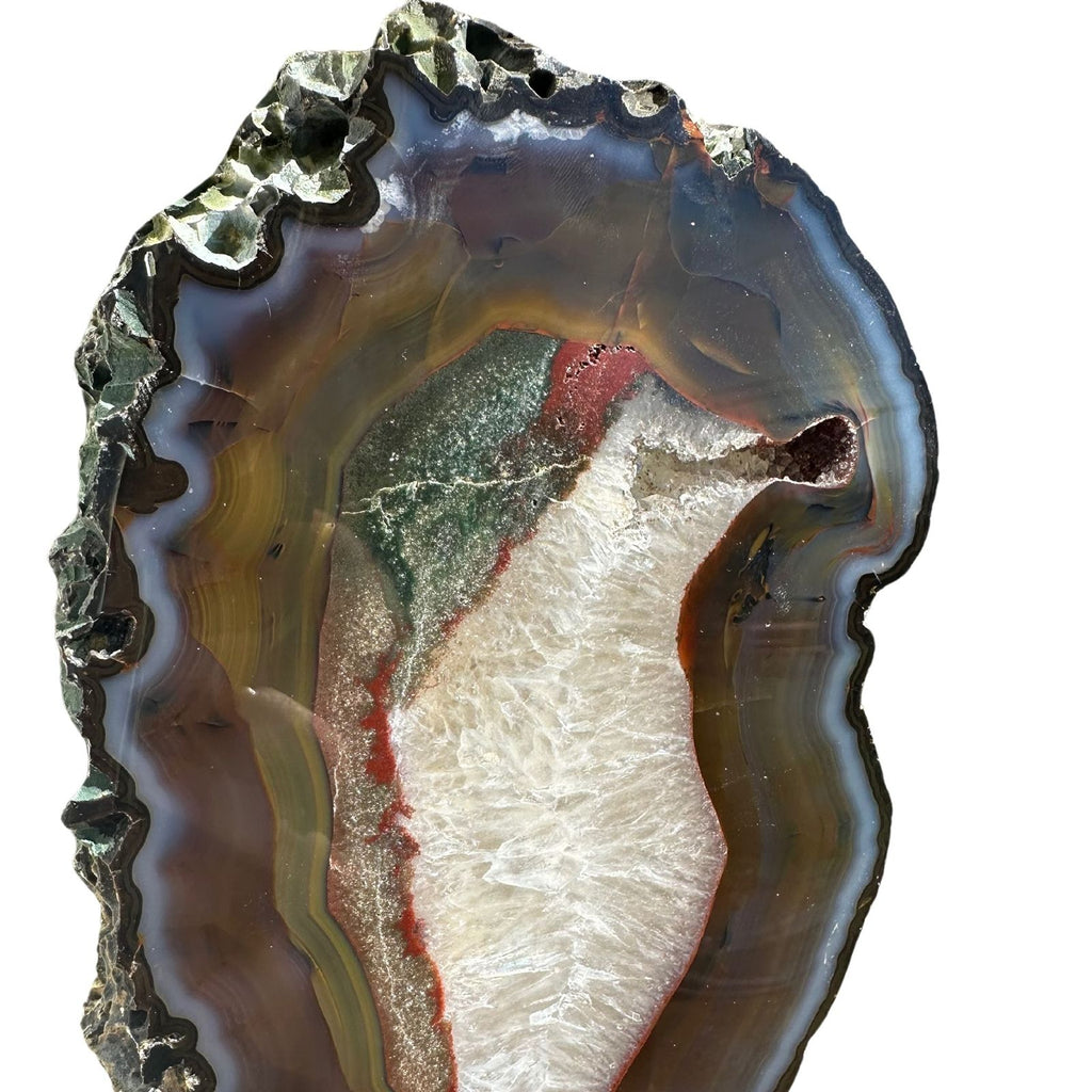 close up view of raw edge and polished front of banded agate crystal slice on a stand