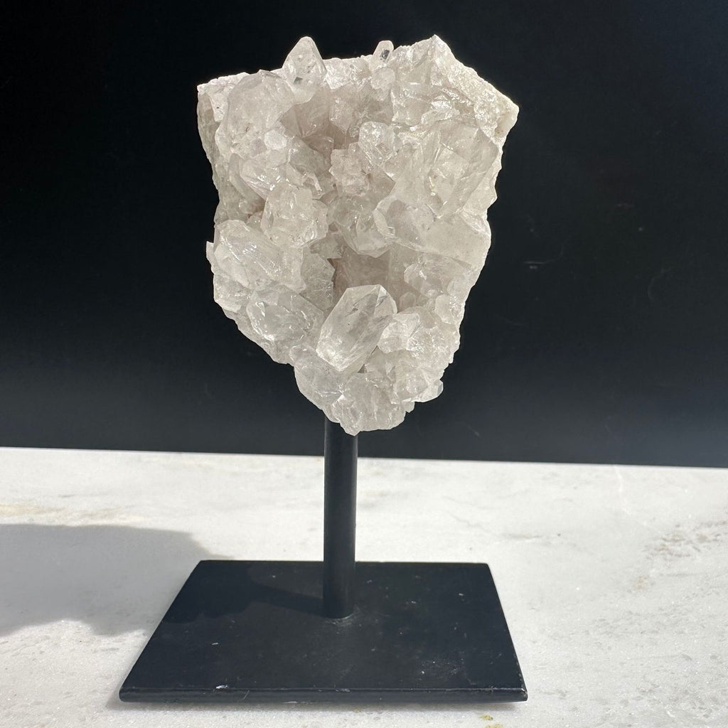 clear quartz crystal cluster with defined quartz points on a stand