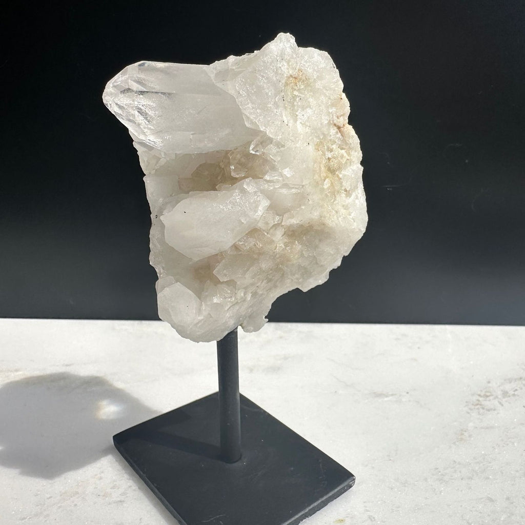 side view of large point in clear quartz crystal cluster