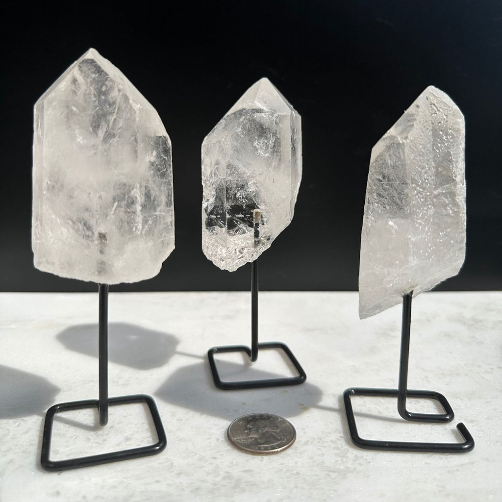 Clear Quartz Crystal Points on a stand next to a quarter for size reference. Crystals from Brazil.