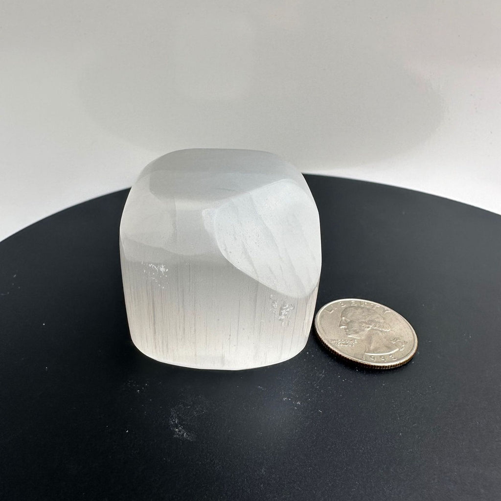 Selenite, Satin Spar, polished cube carving, next to a quarter for size reference