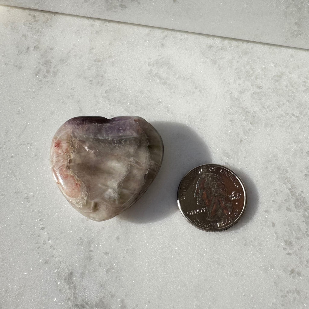 Amethyst heart carving next to a quarter for size reference, and a Brazilian crystal