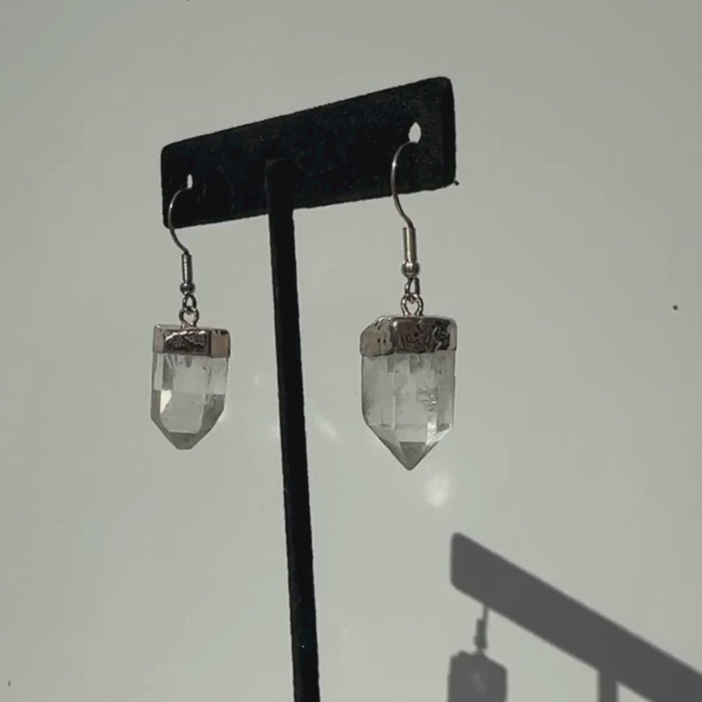 Clear Quartz crystal earrings on a slowly rotating stand to detailed viewing